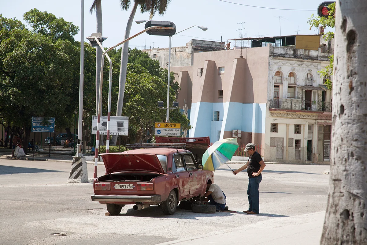 A mechanic is shaded whilst working on a broken-down car in Havana, Cuba.