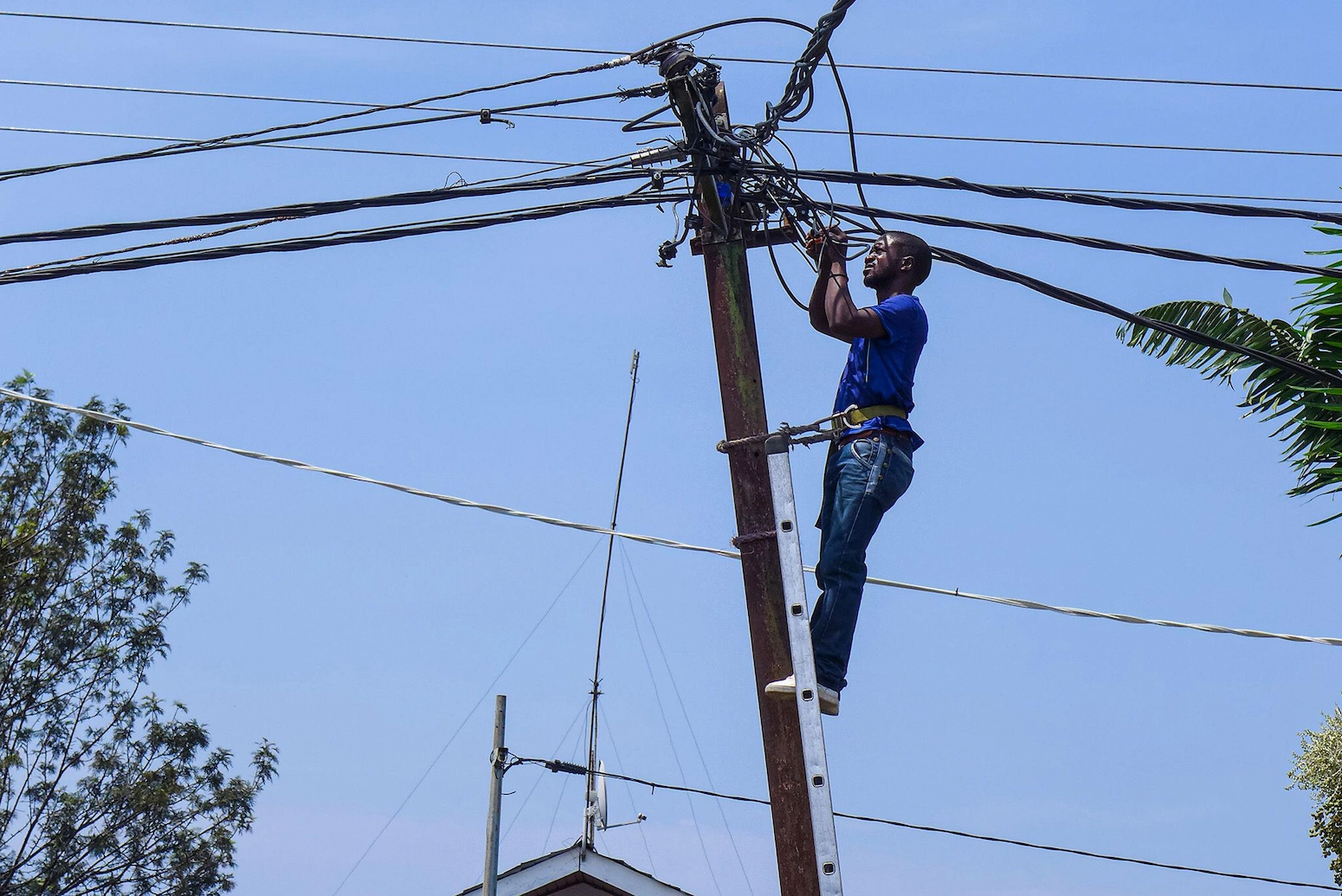Field technician checks a connection on an electrical pole in Goma, DRC